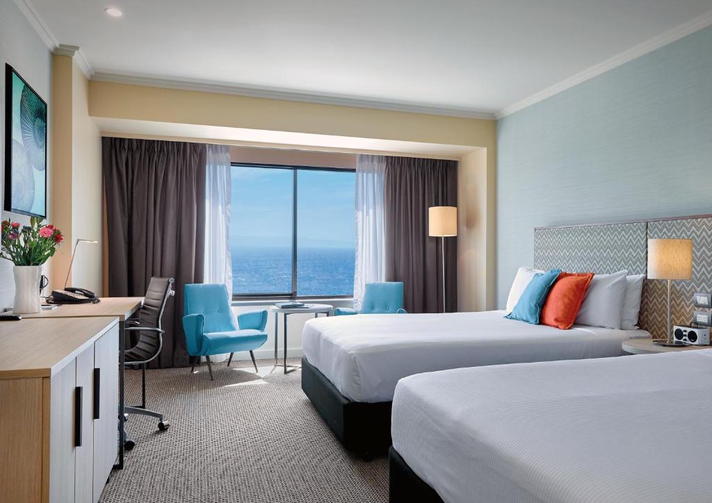 a hotel room with two beds and a desk at Stamford Grand Adelaide in Adelaide