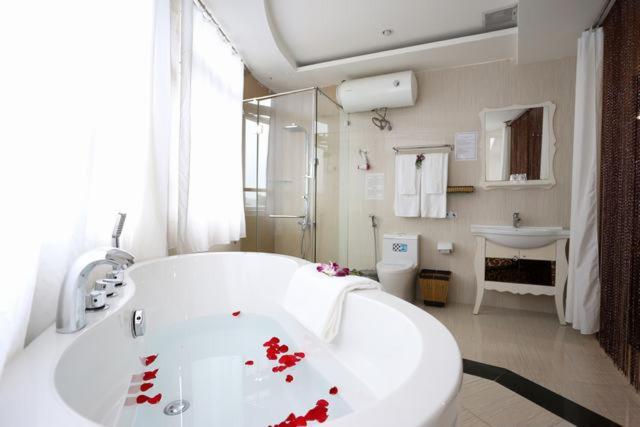 a bathroom with a white tub with red roses on it at Mountain Town Hotel in Da Lat