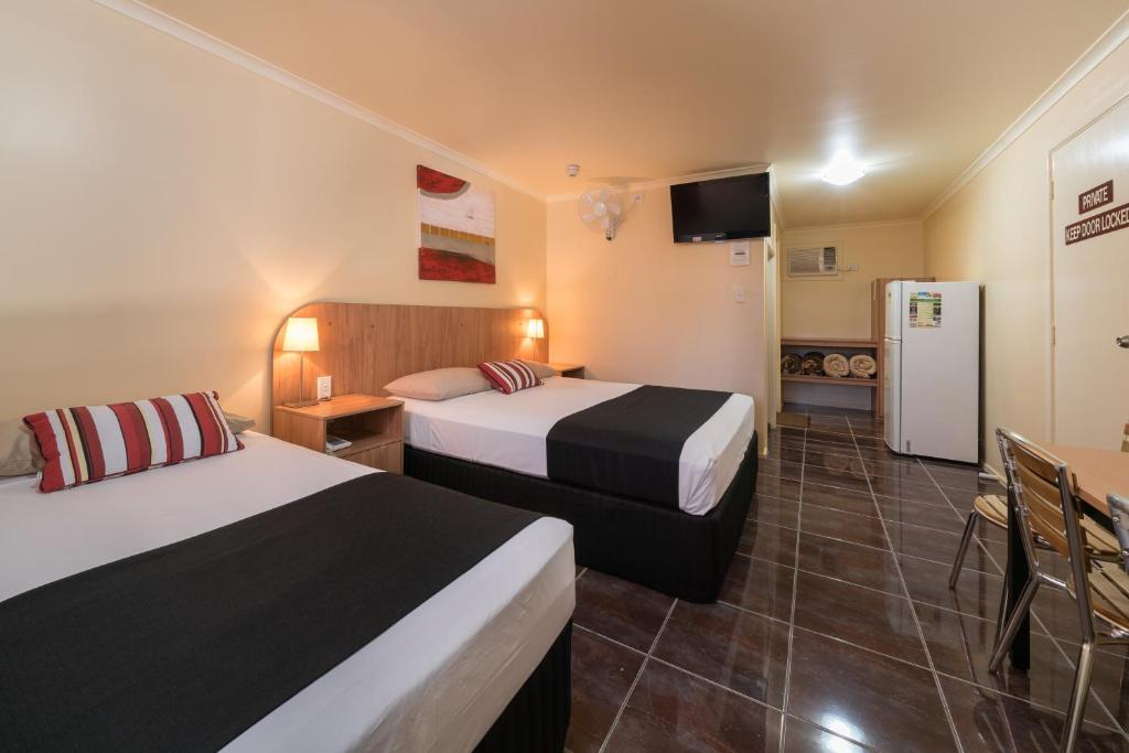 um quarto de hotel com duas camas e um frigorífico em Winter Sun Motel em Rockhampton