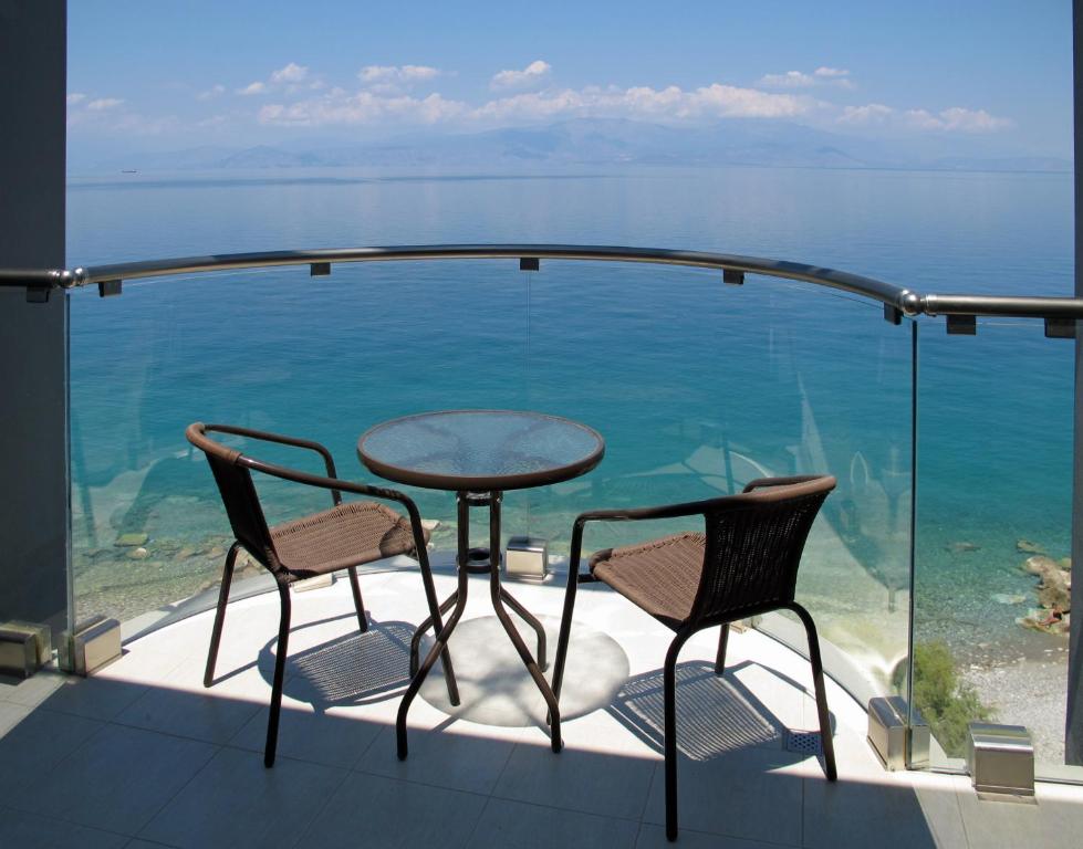 einen Tisch und Stühle auf einem Balkon mit Meerblick in der Unterkunft Arion Hotel in Xylokastro