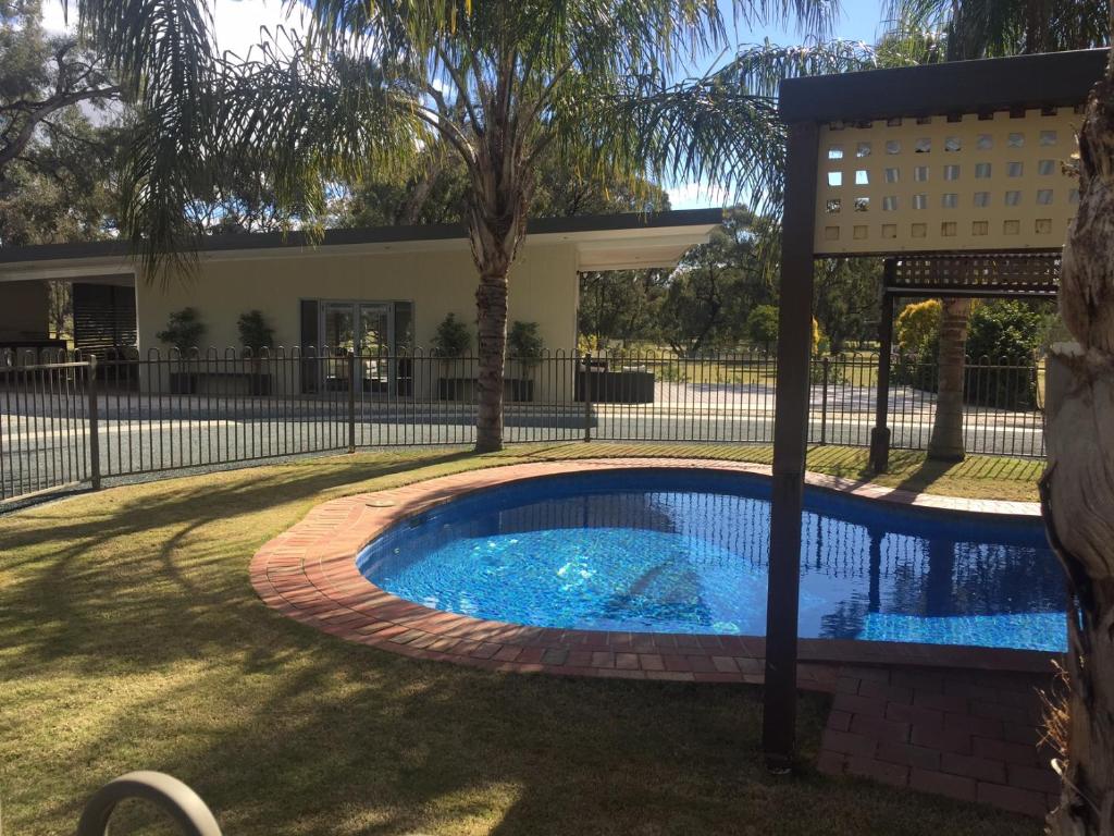a swimming pool in a yard with a fence at Deni Golf Resort in Deniliquin