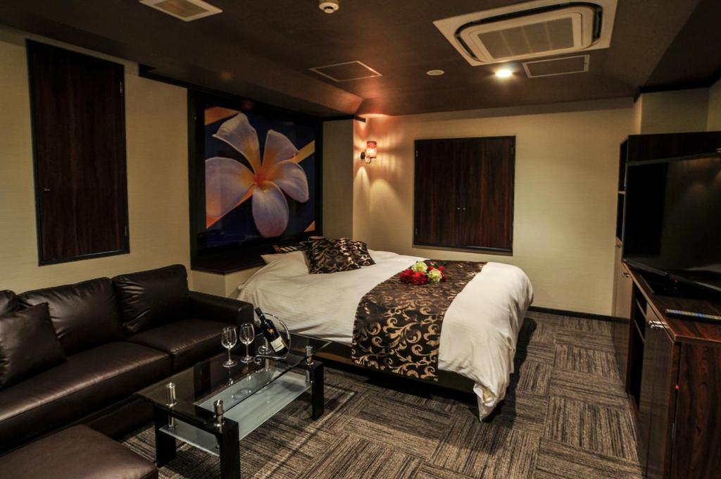 een hotelkamer met een bed en een bank bij Hotel Grande (Love Hotel) in Kitakyushu