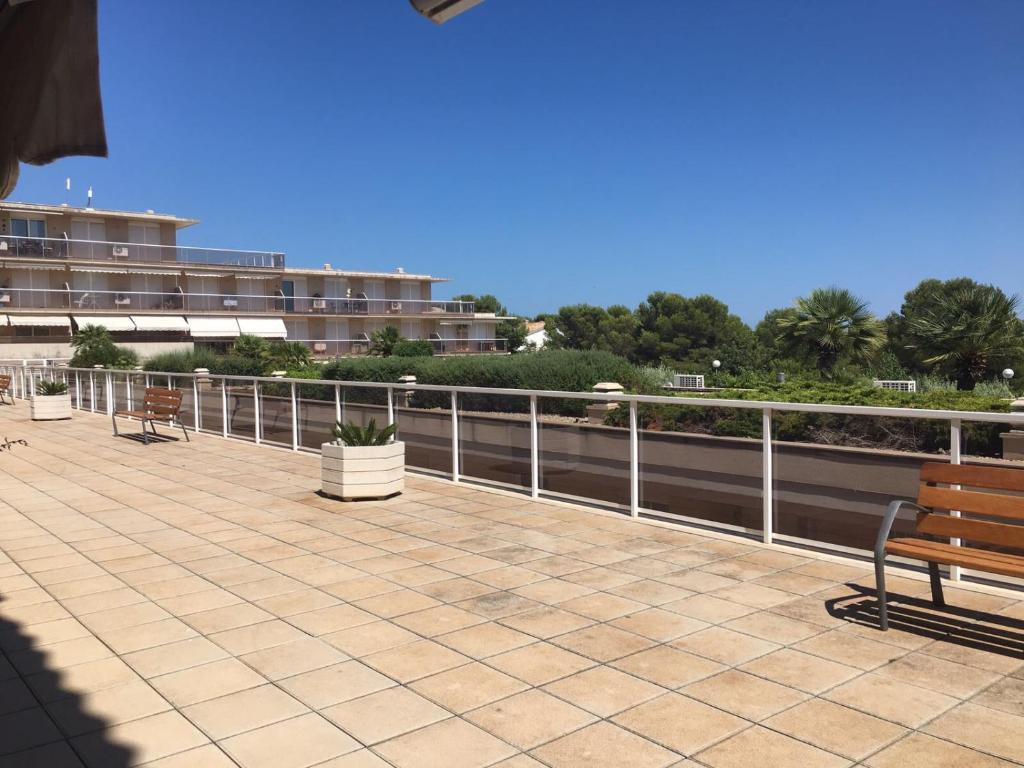 a walkway with two benches and a fence at Apartament Agutzil de Mar in Alcanar