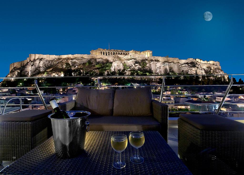 uma mesa com dois copos de vinho numa varanda em Plaka Hotel em Atenas