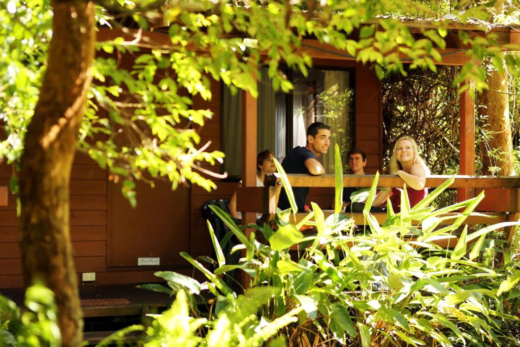 un grupo de personas sentadas en un banco frente a una casa en Samurai Beach Bungalows - Port Stephens YHA, en Anna Bay