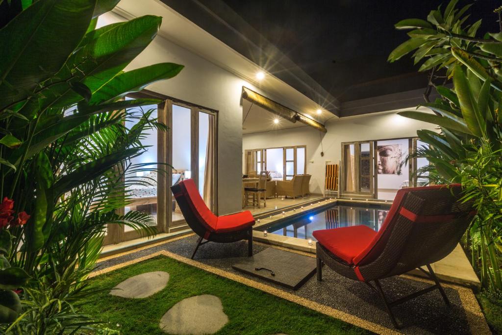 ein Wohnzimmer mit einem Pool und 2 Stühlen in der Unterkunft Castro Villa in Seminyak