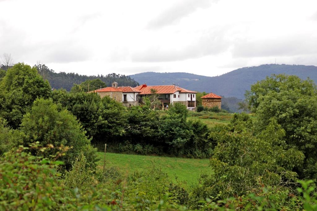 a house in the middle of a field with trees at Hotel Casona Cuervo in San Tirso de Candamo