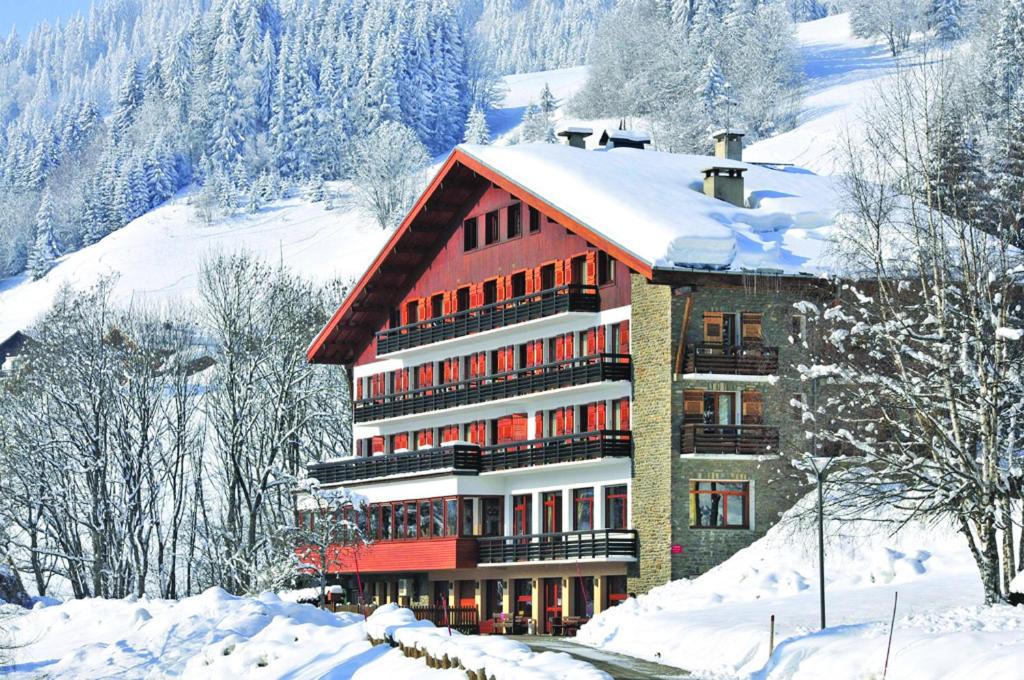 a large building in the snow with snow covered trees at Hôtel Vacances Bleues Les Chalets du Prariand in Megève