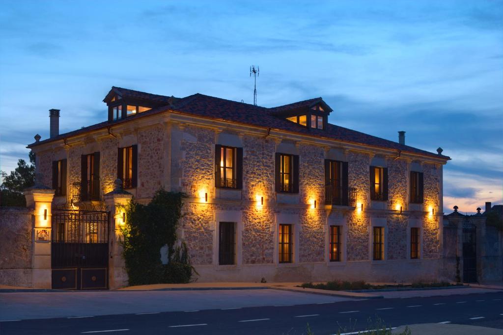 a large stone building with lights on it at El Señorio De La Serrezuela in Aldeanueva De La Serrezuela 