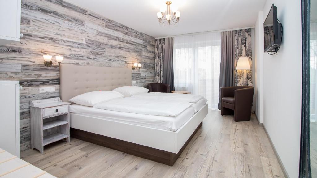 a bedroom with a white bed and a stone wall at Hotel Diana Garni in Malente