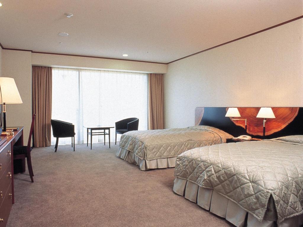 屋久島にある屋久島いわさきホテルのベッド2台と机があるホテルの部屋
