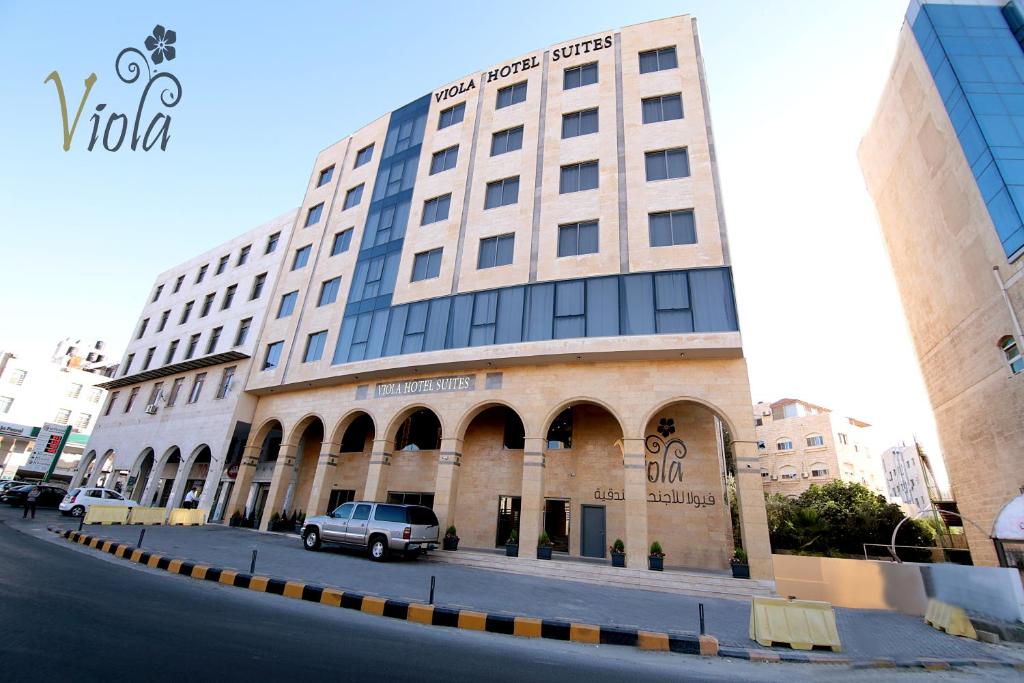 een auto geparkeerd voor een groot gebouw bij Viola Hotel Suites in Amman