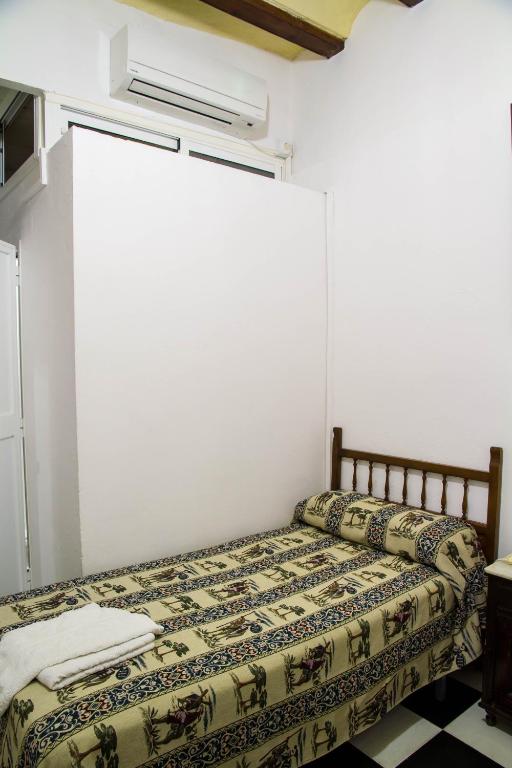 a bed in a room with avertisementatronatronstrationstrationstration at Pensión San Benito Abad in Seville