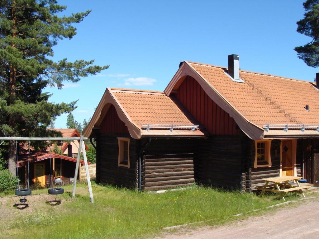 Cabaña de madera con techo rojo en Tomtelandstugan, en Mora