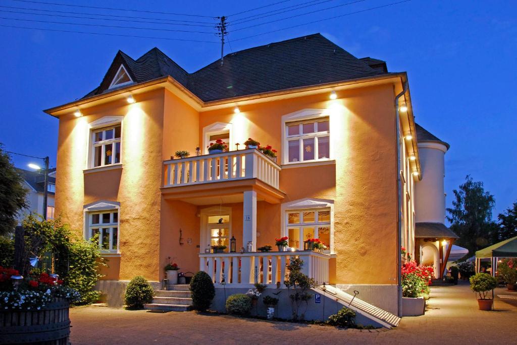 Una gran casa amarilla con balcón por la noche en Weingut und Gästehaus Apel en Nittel