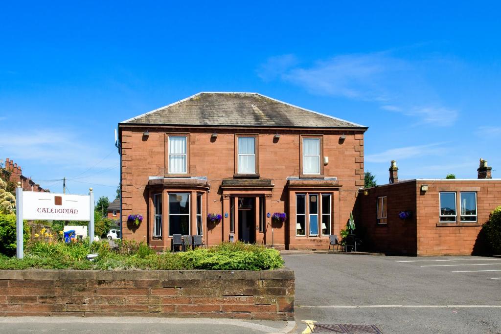 een stenen huis met een bord ervoor bij Caledonian Hotel in Dumfries