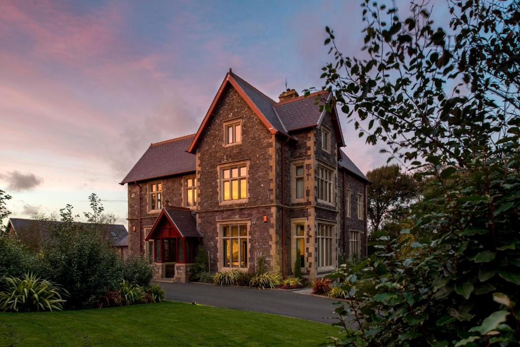 a large brick house with the sun shining on it at Penrhiw Priory in St. Davids