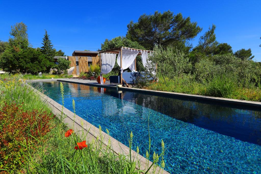 a swimming pool with blue water in a yard at Bien Loin d'Ici Spa B&B in Nîmes
