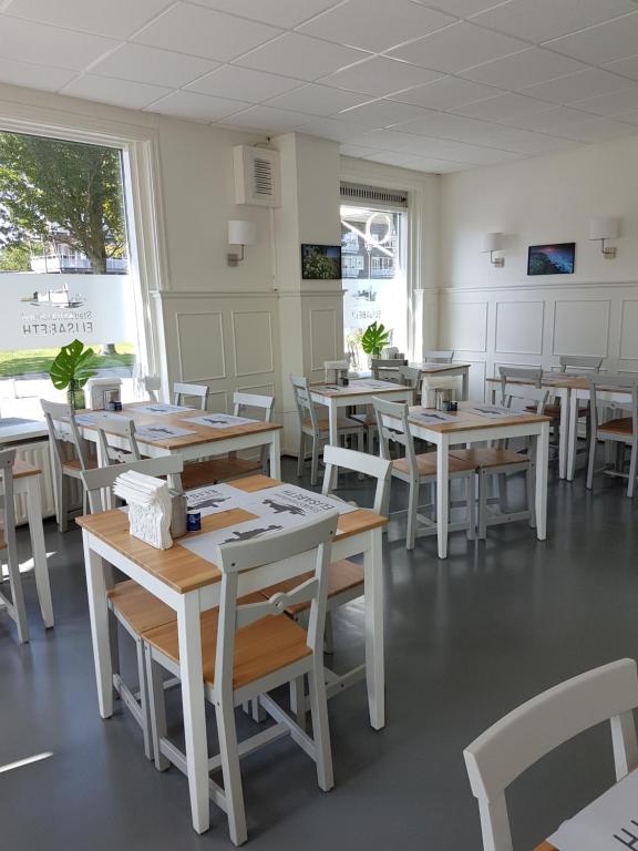 a dining room with wooden tables and white chairs at Stad &amp; Strandhotel Elisabeth in Vlissingen