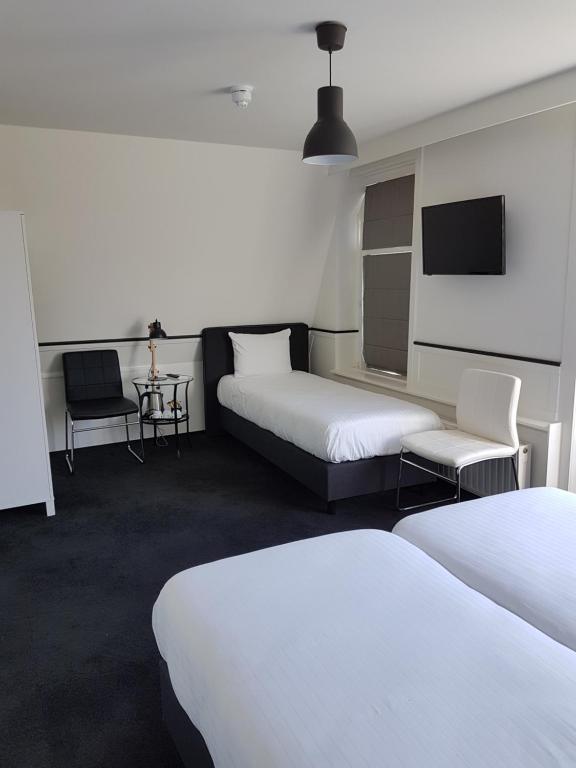 a hotel room with two beds and a flat screen tv at Stad &amp; Strandhotel Elisabeth in Vlissingen