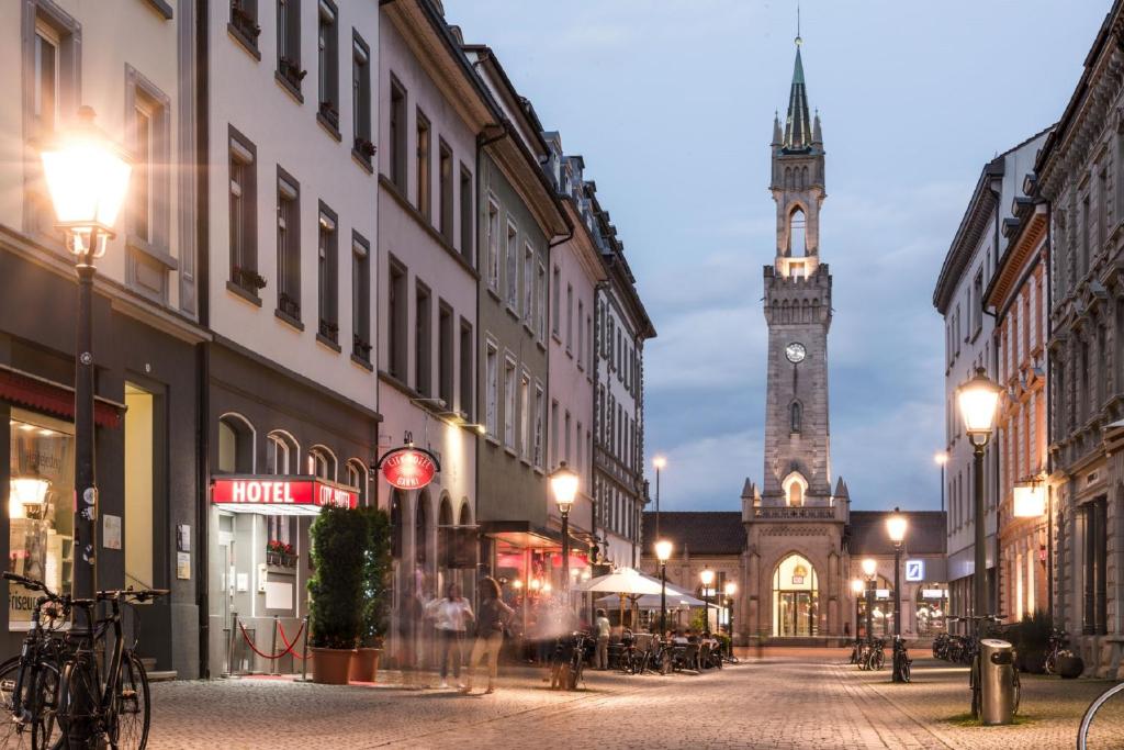 una calle de la ciudad con una torre de reloj en la distancia en City Hotel Konstanz en Constanza