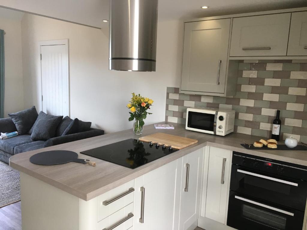 a kitchen with a counter top and a living room at Little Fernleigh in Perranporth