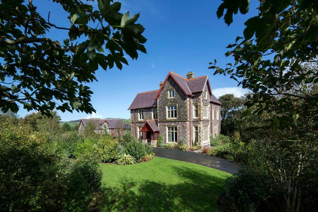 an old house with a green lawn in front of it at Penrhiw Priory in St. Davids