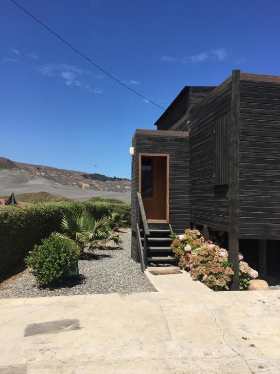 ein Holzhaus mit einer Treppe, die zur Tür führt in der Unterkunft Casa Playa in Navidad