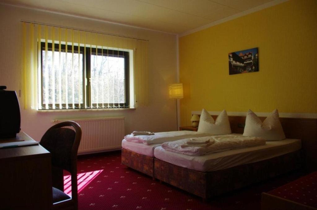 a hotel room with a bed and a window at Landhotel &amp; Restaurant Kains Hof in Uhlstädt