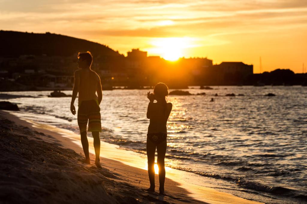 2 personnes debout sur la plage au coucher du soleil dans l'établissement Joseph Charles, à LʼÎle-Rousse