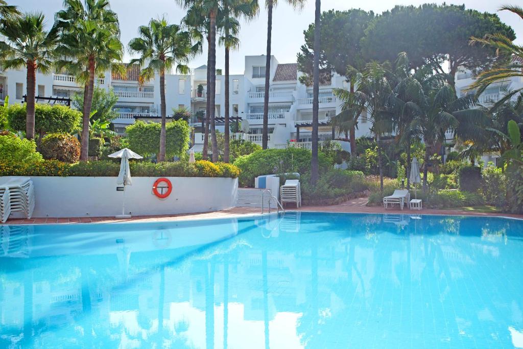 a large swimming pool with palm trees and a building at White Pearl Beach Elviria in Marbella