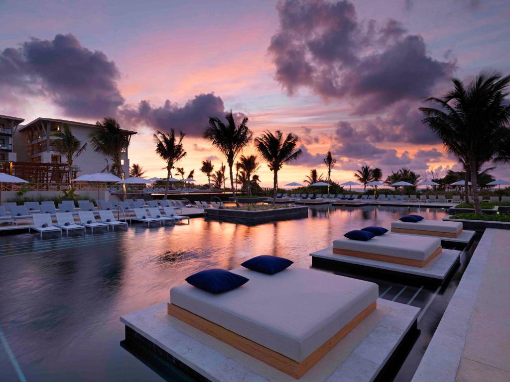 a resort with two beds and chairs and a pool at Unico Hotel Riviera Maya Adults Only in Akumal