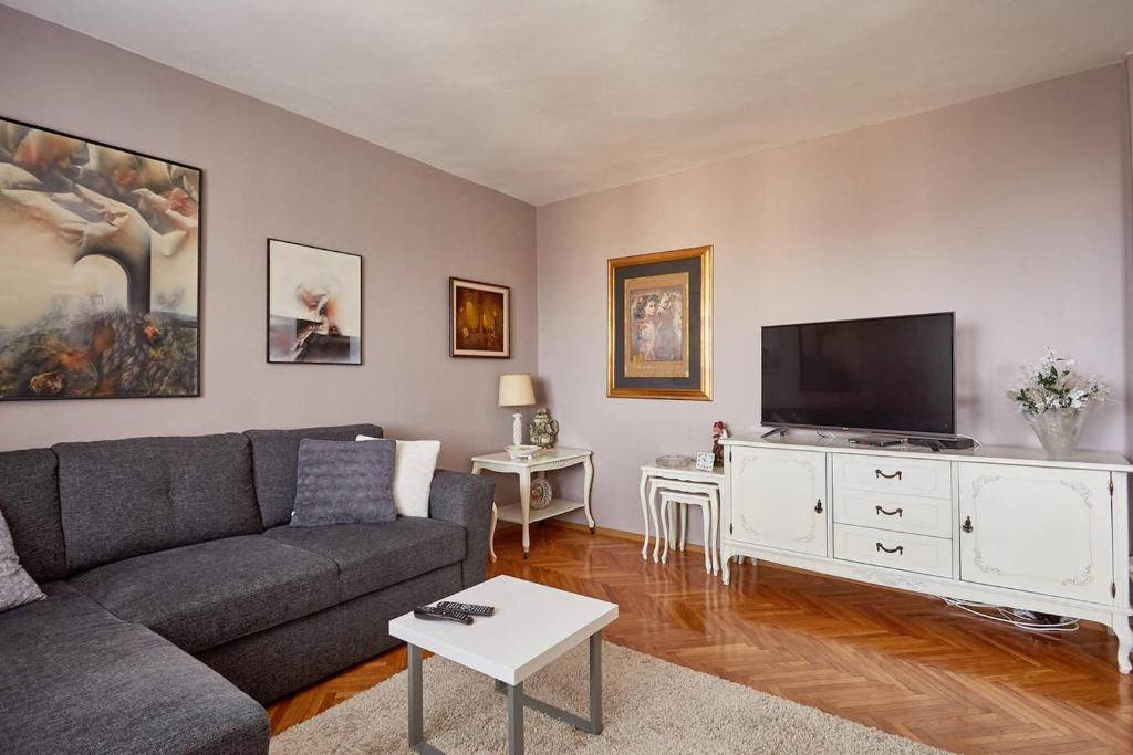 een woonkamer met een bank en een flatscreen-tv bij Spacious modern apartment in peaceful neighborhood in Skopje