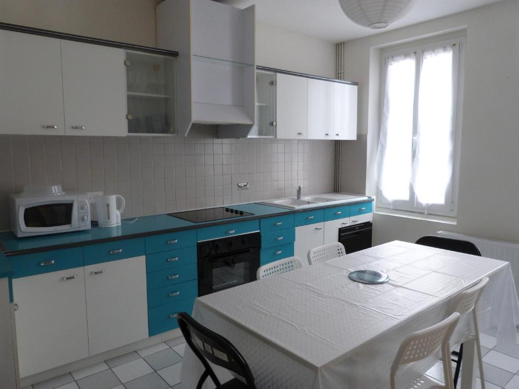 eine Küche mit blauen Schränken und einem Tisch mit Stühlen in der Unterkunft La petite maison de Lilou in Romilly-sur-Seine