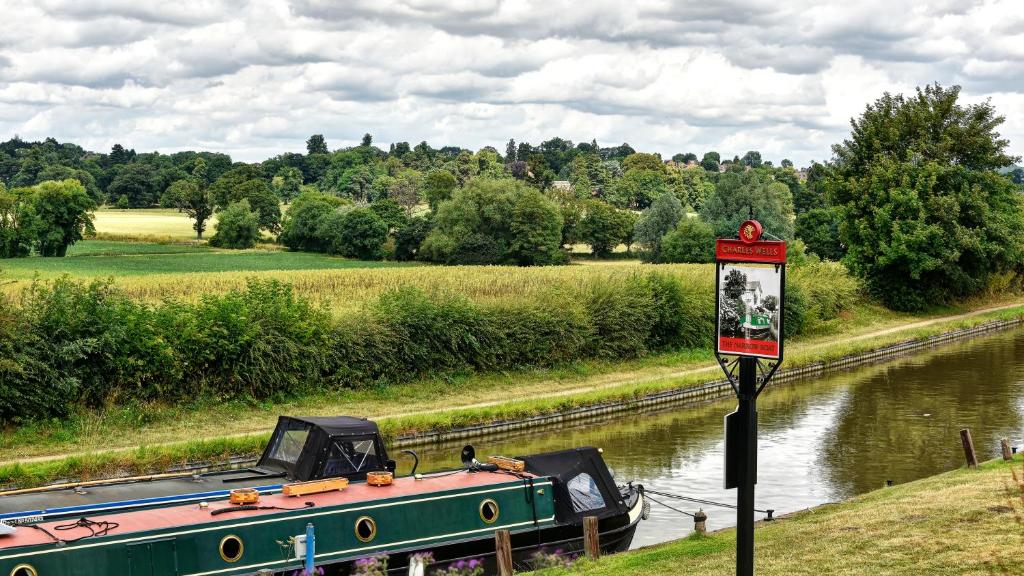 a boat is docked on the side of a river at Narrowboat at Weedon in Weedon Bec