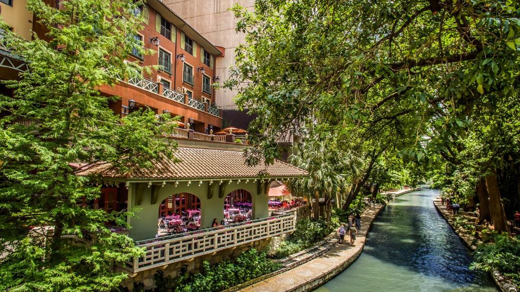 a river in front of a building next to a building at Hotel Valencia Riverwalk in San Antonio