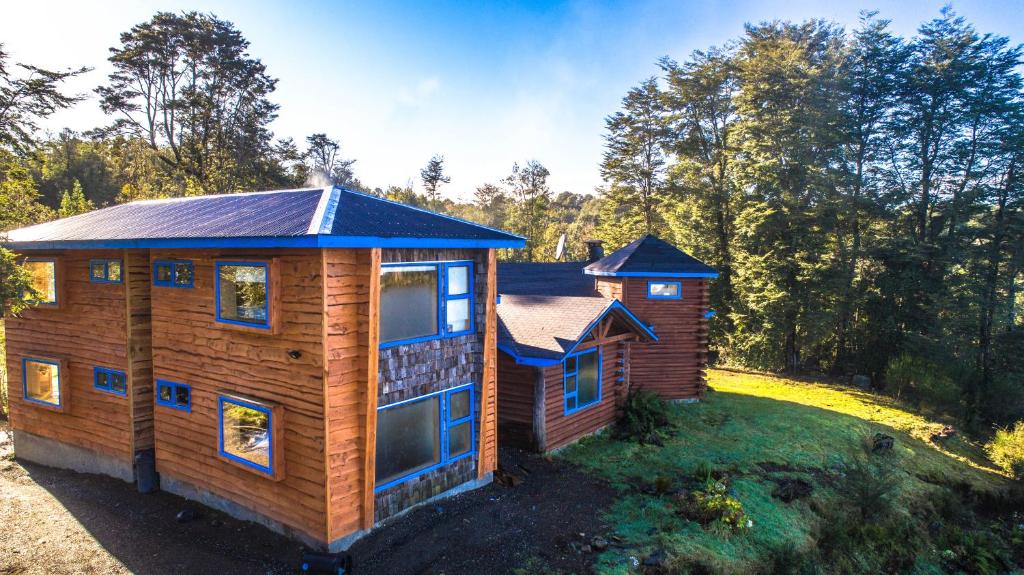 uma cabana de madeira com um telhado azul num quintal em Hostal Casa Bosque em Dalcahue