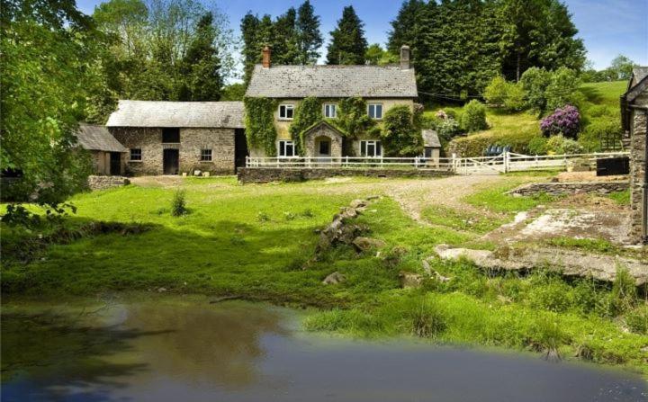 an old house on a hill next to a river at Zeal Farm in Dulverton