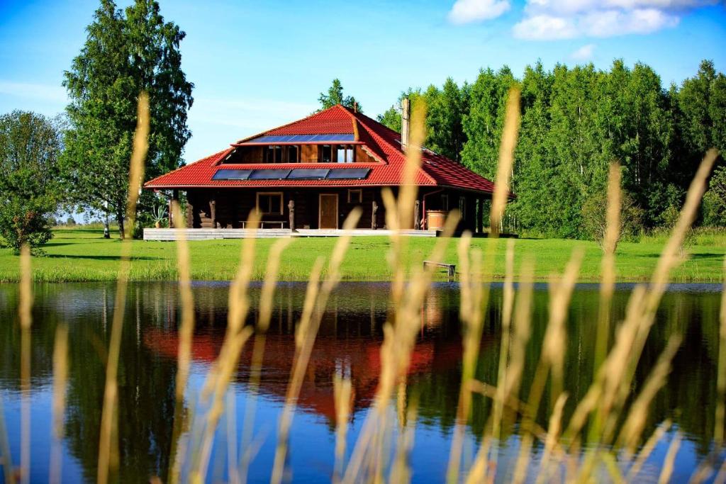 ein Haus mit rotem Dach neben einem See in der Unterkunft Agave in Augšlīgatne