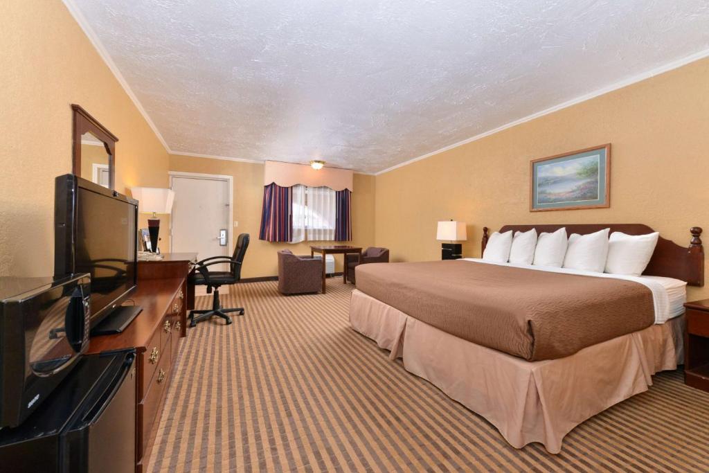 Executive Plus Inn and Suites في إيلك سيتي: غرفة فندقية بسرير وتلفزيون بشاشة مسطحة
