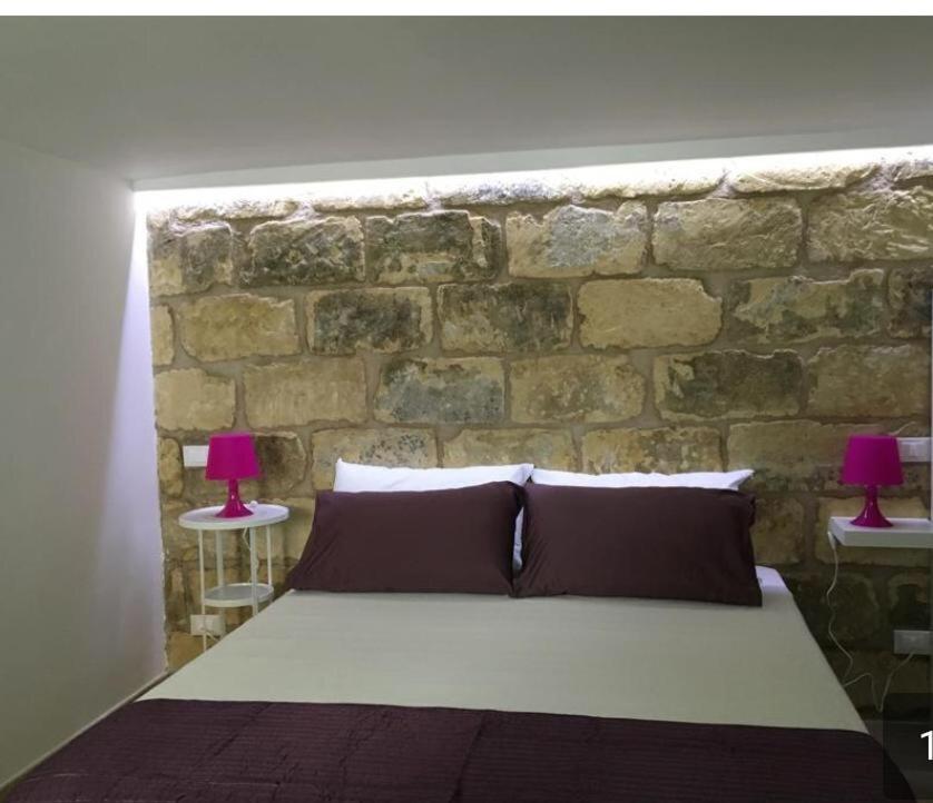 サン・ヴィート・ロ・カーポにあるFresco Mare Bluの石壁のベッドルーム1室(ランプ2つ付きのベッド1台付)