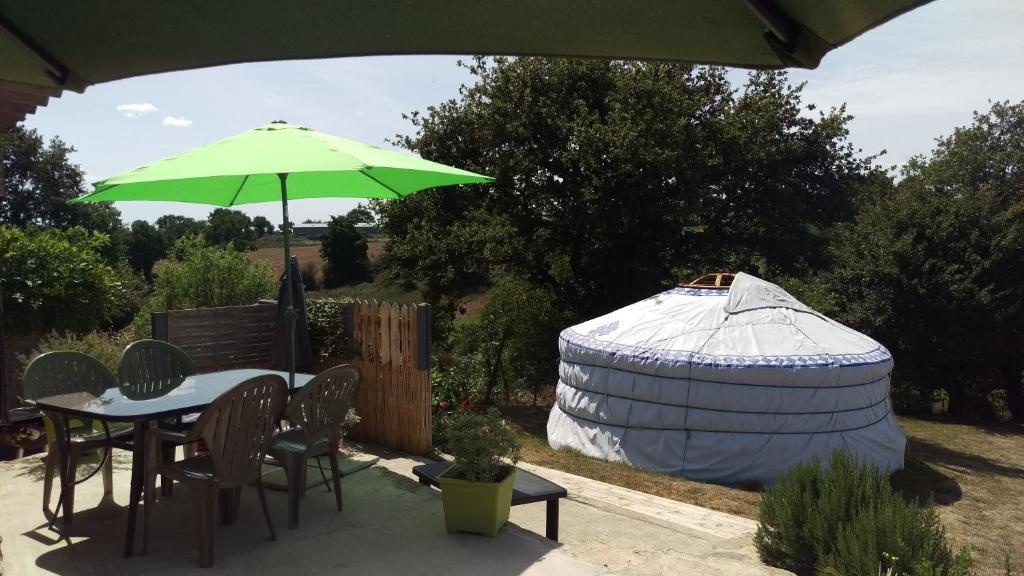 une grande yourte et une table avec un parasol vert dans l'établissement Aux Yourtes de La Fabrique, à Saint-Florent-des-Bois