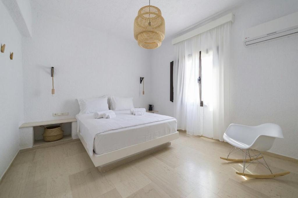 a white bedroom with a white bed and a white chair at En Lefko in Sitia