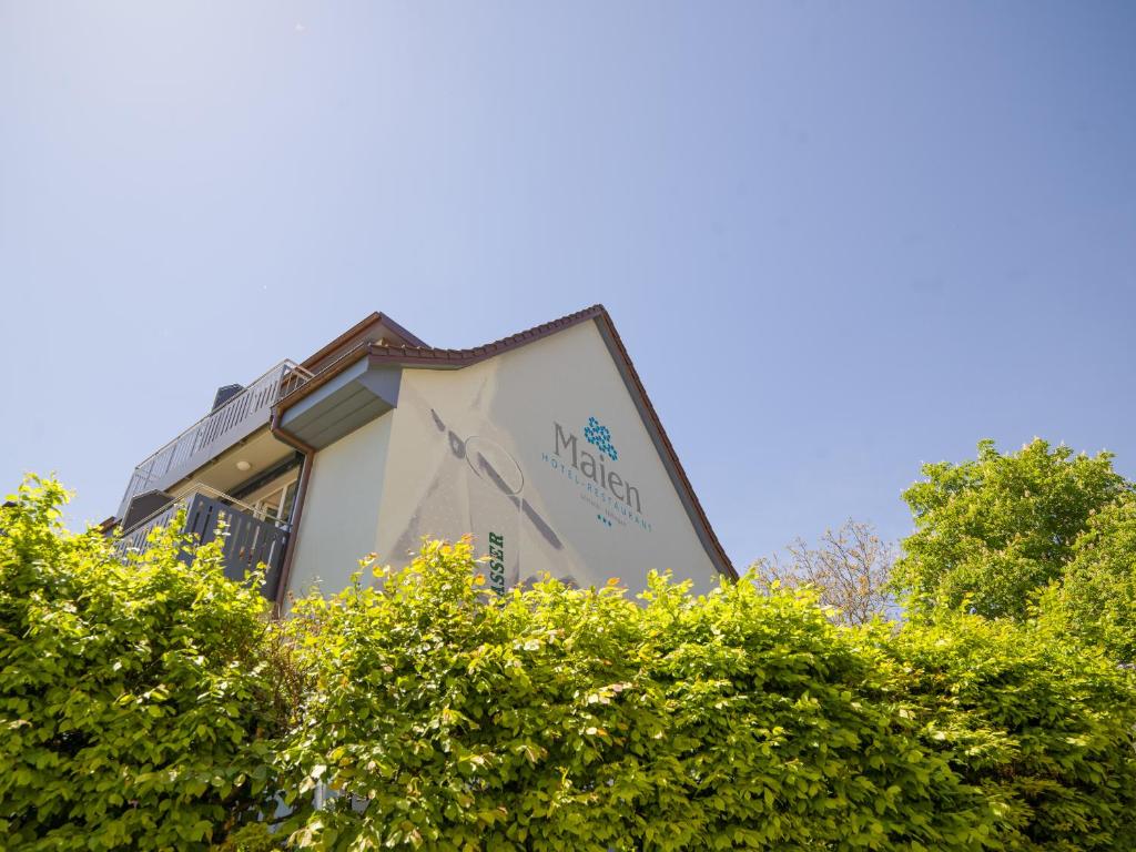 un panneau sur le côté d'un bâtiment derrière quelques buissons dans l'établissement Restaurant-Hotel Maien, à Lörrach