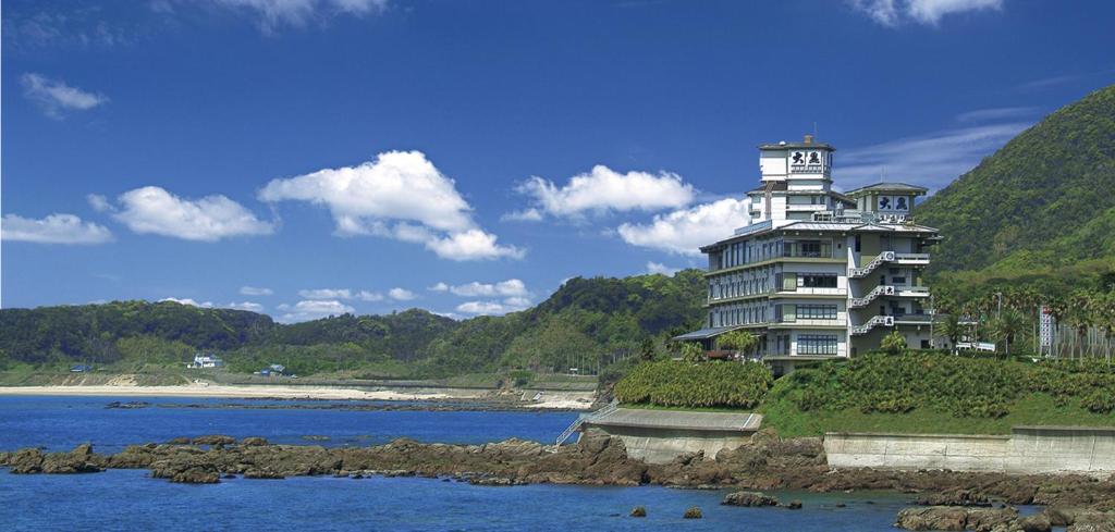 a building on a hill next to a body of water at Shibushiwan Daikoku Resort Hotel in Shibushi
