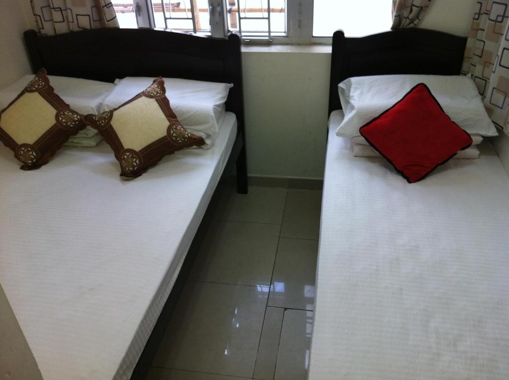 2 letti in una camera con cuscino rosso di Hung Fai Guest House a Hong Kong