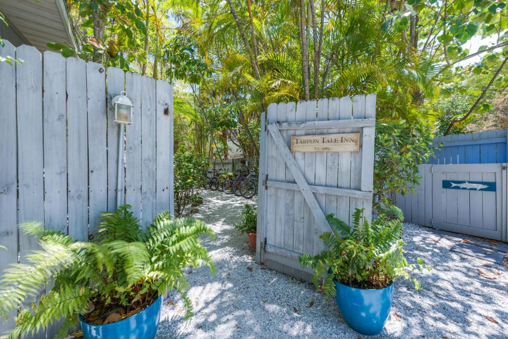 a fence with a wooden gate and two plants at Tarpon Tale Inn in Sanibel