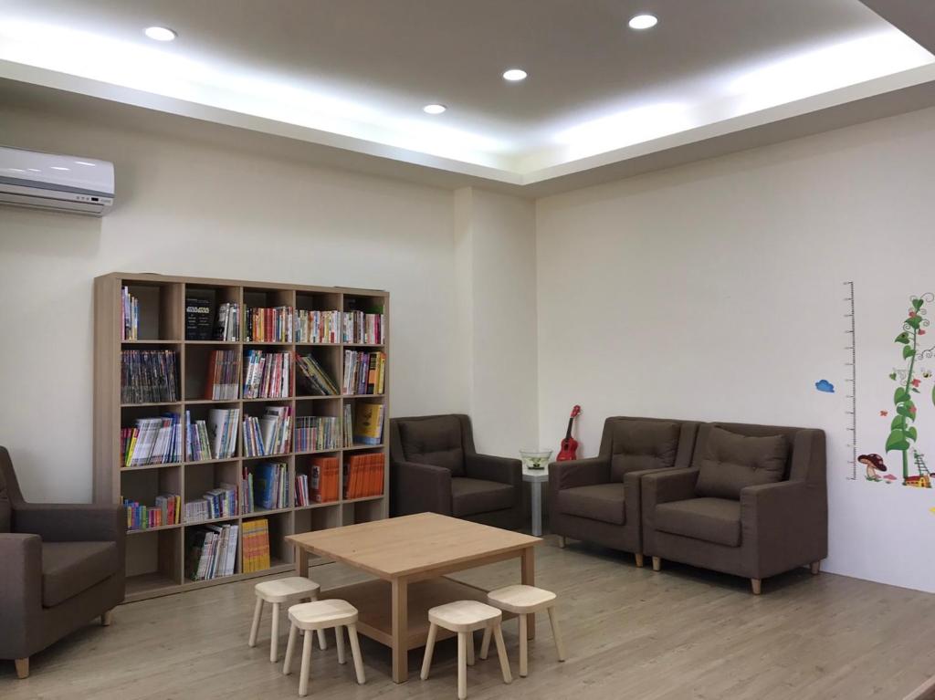 台東市的住宿－享飛親子民宿，一个带沙发和桌子的图书馆和一个书架