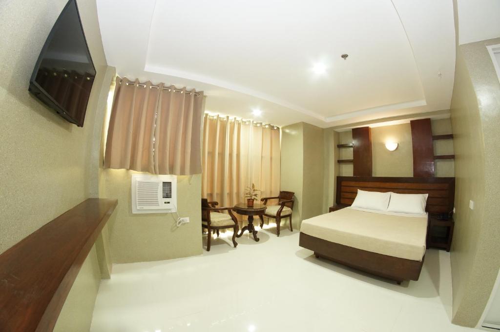 a hotel room with a bed and a table at Hotel Rodolfo in Tacloban