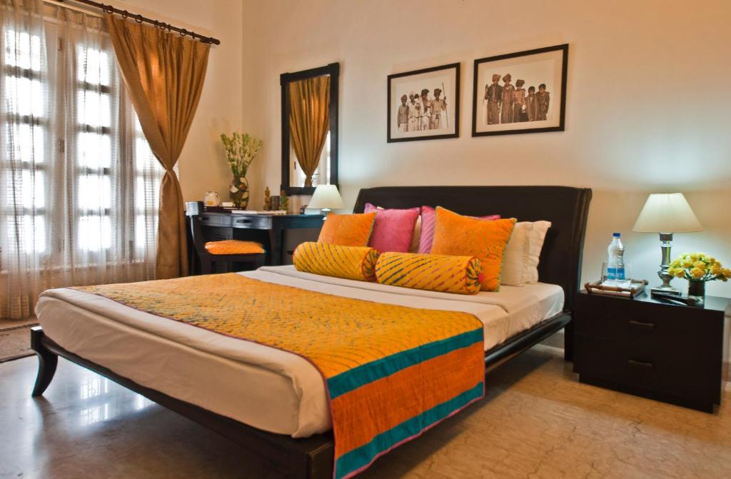 1 dormitorio con 1 cama grande y almohadas coloridas en Colonel’s Retreat en Nueva Delhi